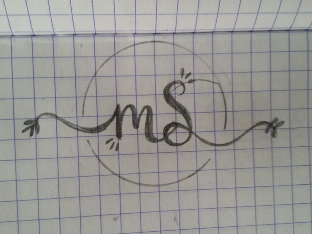 Pencil sketch on squared paper of a script monogram MS inside a thin circle, with a curling line and small leaves running out on both sides.